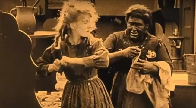 Η «μαύρη» υπηρέτρια είναι άντρας με μακιγιάζ. Επιχειρείται σύνδεση των «αδρών» χαρακτηριστικών με υπόνοιες «κατώτερης» φυλής